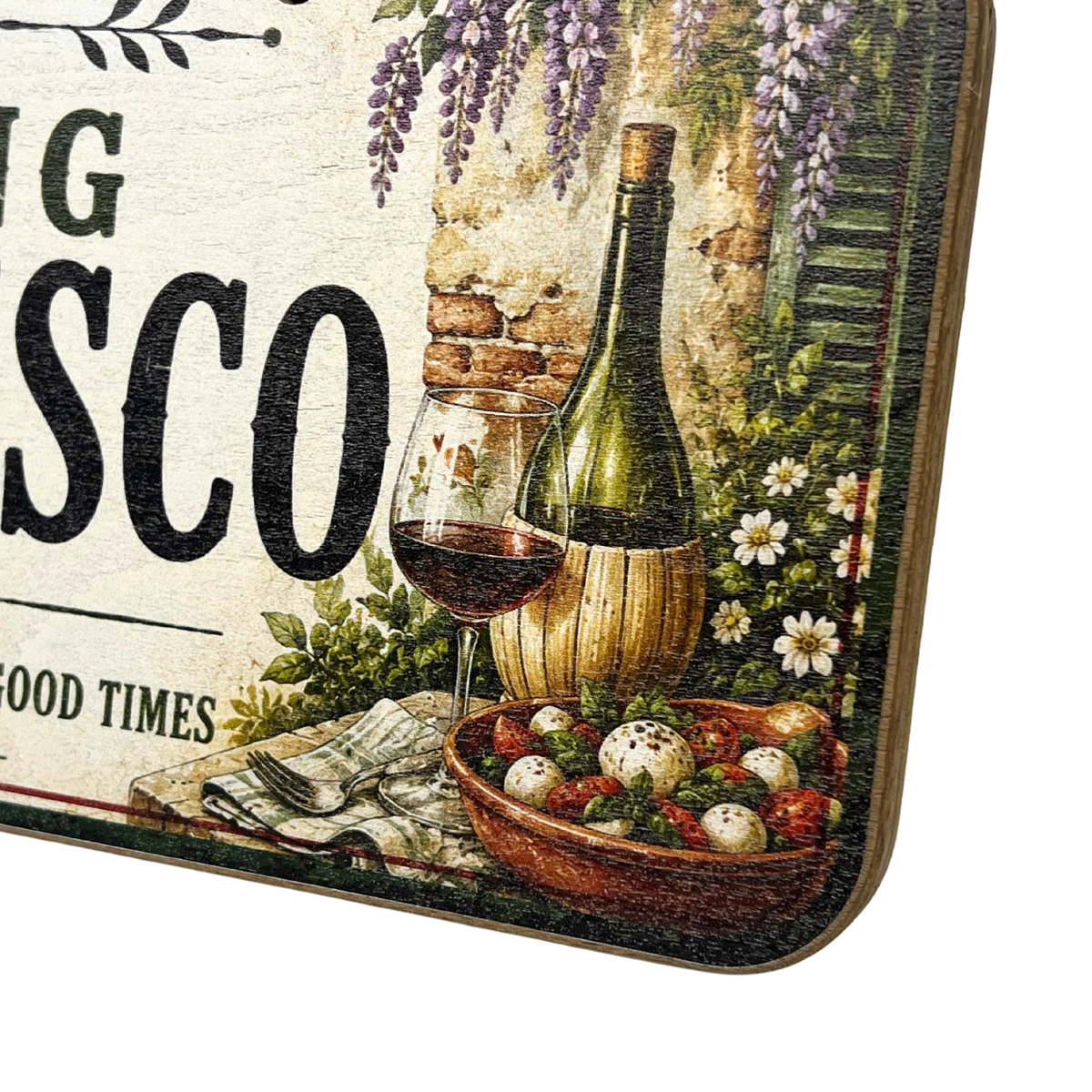 A close-up of a decorative sign or plaque featuring a vintage-style wine still life with a bottle, wine glass, flowers, and a bowl of food on a cream background with large black text.