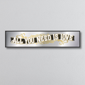 Decorative mirror sign with 'All You Need Is Love' art deco style text on a gray background