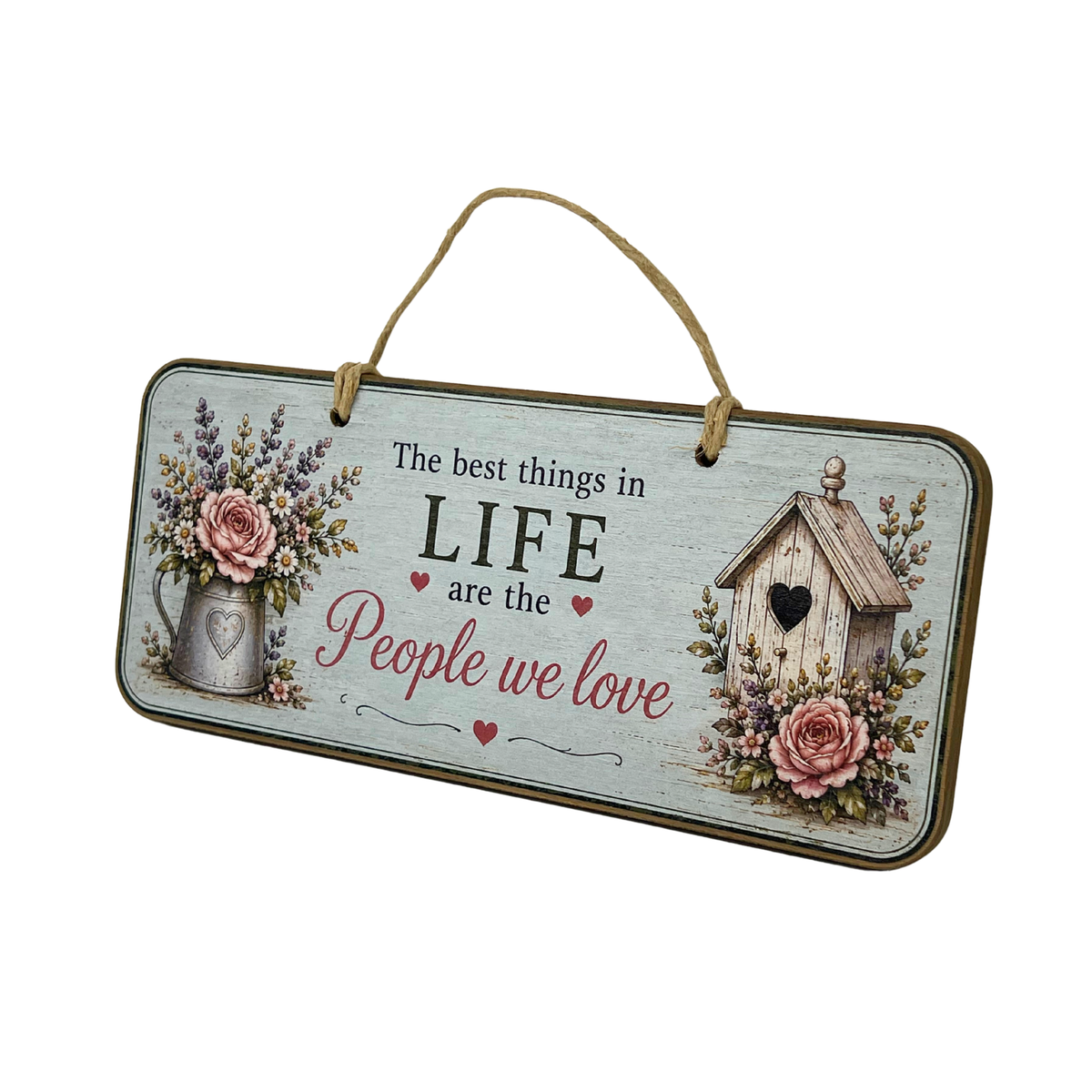 A rectangular hanging wall sign with a rustic distressed light blue-gray background, featuring the phrase 'The best things in LIFE are the People we love' in black and pink script. The sign is decorated with pink roses, a metal pitcher with flowers, and a small birdhouse, and hangs from a jute rope against a plain white background.