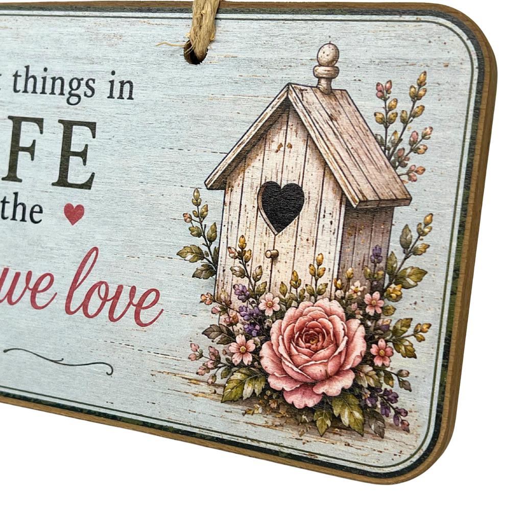 A rustic decorative hanging sign with a whitewashed wood background, a printed birdhouse and floral illustration, and partial text reading 'things in LIFE we love.'.