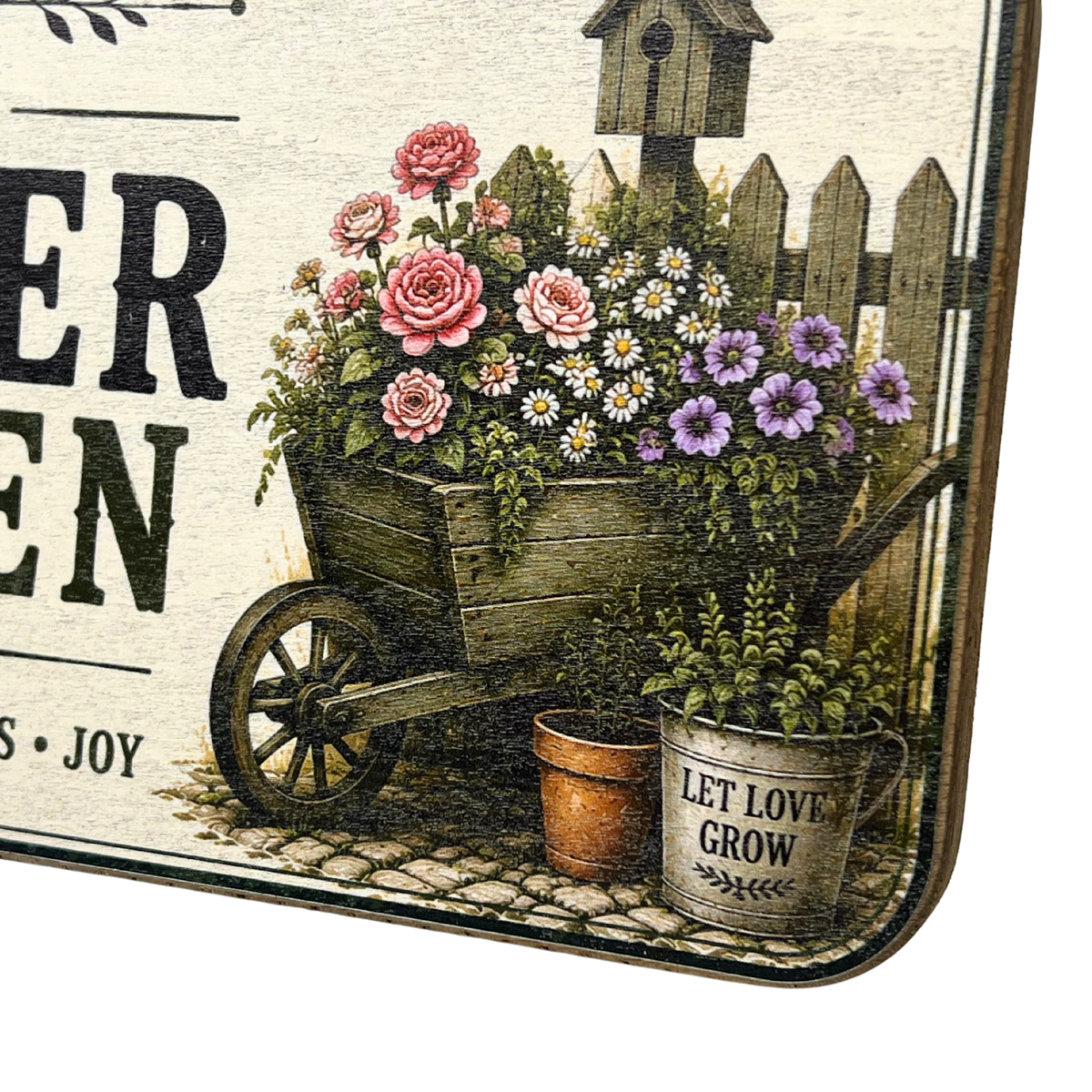 A decorative square sign with a vintage garden illustration, showing a wooden cart filled with pink and purple flowers, a small birdhouse, a picket fence, and potted plants. Part of the text reads 'ER EN' and 'S • JOY', and one pot says 'LET LOVE GROW'.