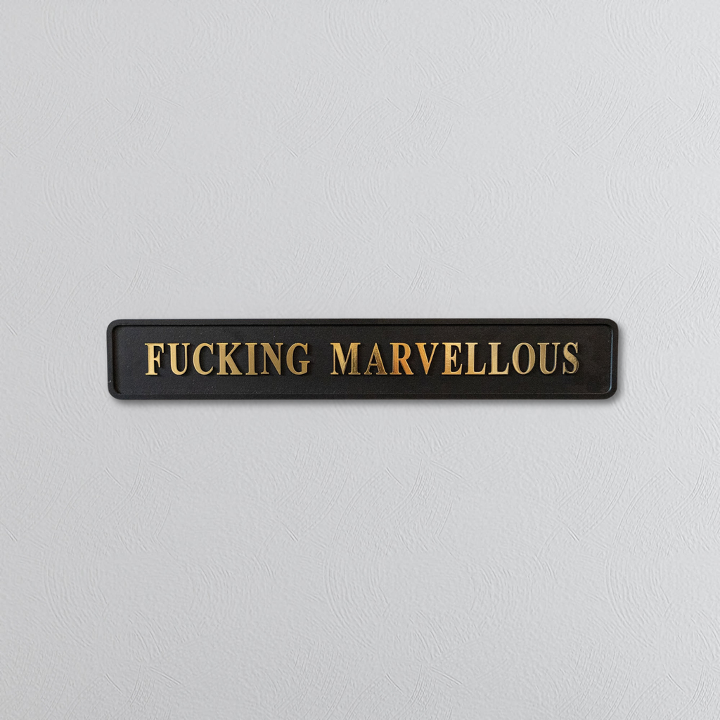 Rectangular sign with 'FUCKING MARVELLOUS' gold text on a light gray background