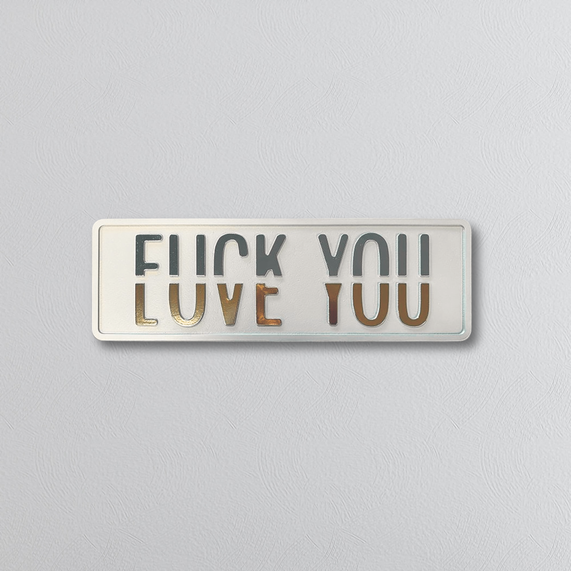 Decorative rectangluar sign with text split horizontally, the top saying FUCK YOU and the bottom LOVE YOU