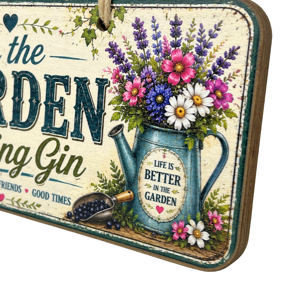 A rectangular decorative garden sign with a rustic distressed cream background and a hanging loop at the top. The sign features large dark teal lettering, a blue watering can filled with colorful flowers, green foliage, and smaller decorative text including 'LIFE IS BETTER IN THE GARDEN' 
