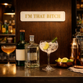Decorative cream and gold sign reading I'M THAT BITCH above a cosy home bar set up