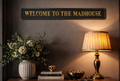 Black and gold foiled street sign with "welcome to the madhouse" wording in a stylish, cosy setting