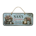 A rectangular hanging wooden sign with a rustic design for 'Nan's Garden'. The sign features a light blue weathered wood background with illustrations of a flower cart, a watering can, a small birdhouse, and potted flowers.