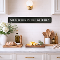 Kitchen counter with 'No Bitchin' in the Kitchen' sign, lemons, bread, and utensils.