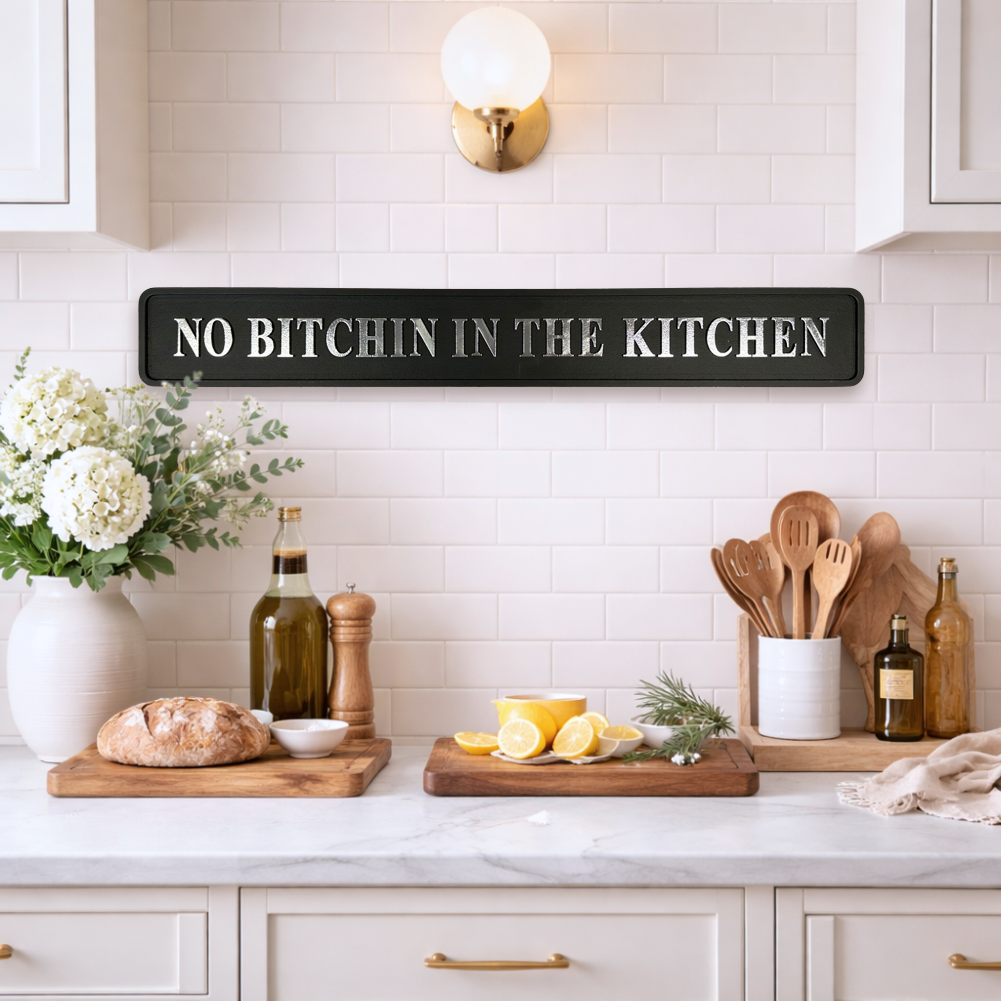 Kitchen counter with 'No Bitchin' in the Kitchen' sign, lemons, bread, and utensils.