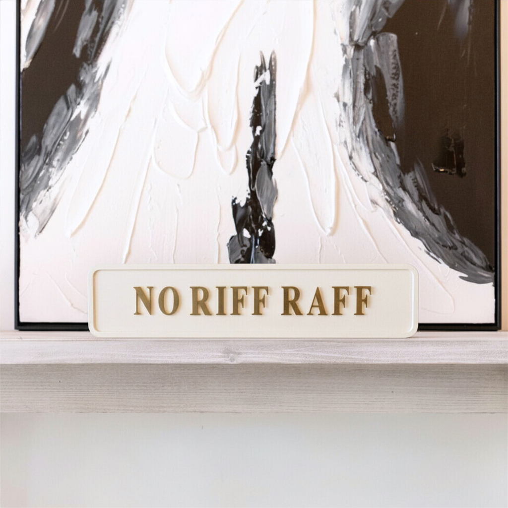 Decorative sign with 'NO RIFF RAFF' text in front of an abstract painting.