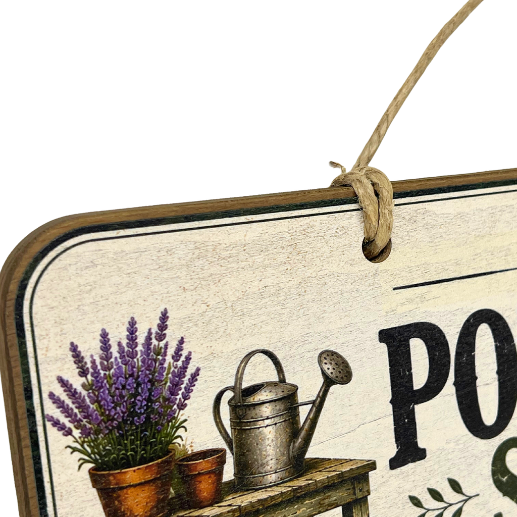 A rustic decorative hanging sign with a weathered cream background, black lettering, and illustrations of purple lavender in small pots and a metal watering can on a wooden bench. A natural twine loop hangs from the top edge.