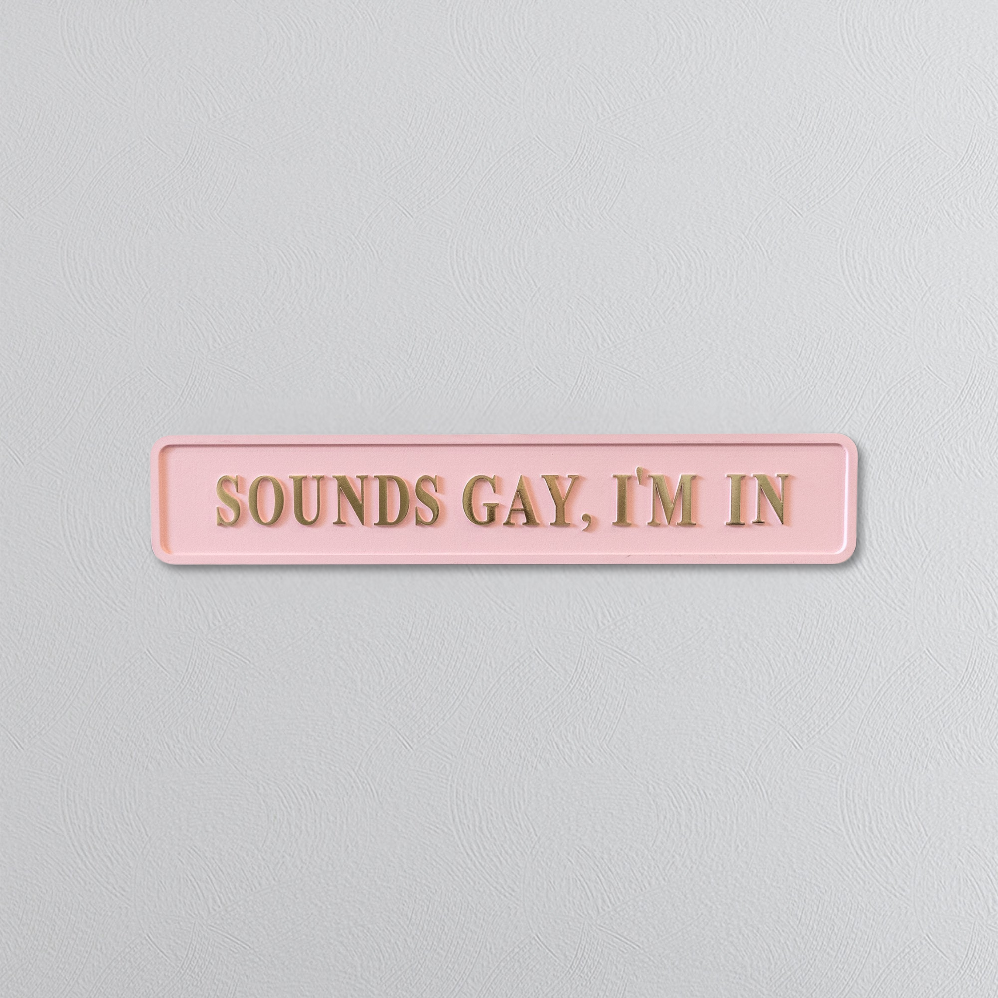 Pink sign with gold text 'SOUNDS GAY, I'M IN' on a light gray background