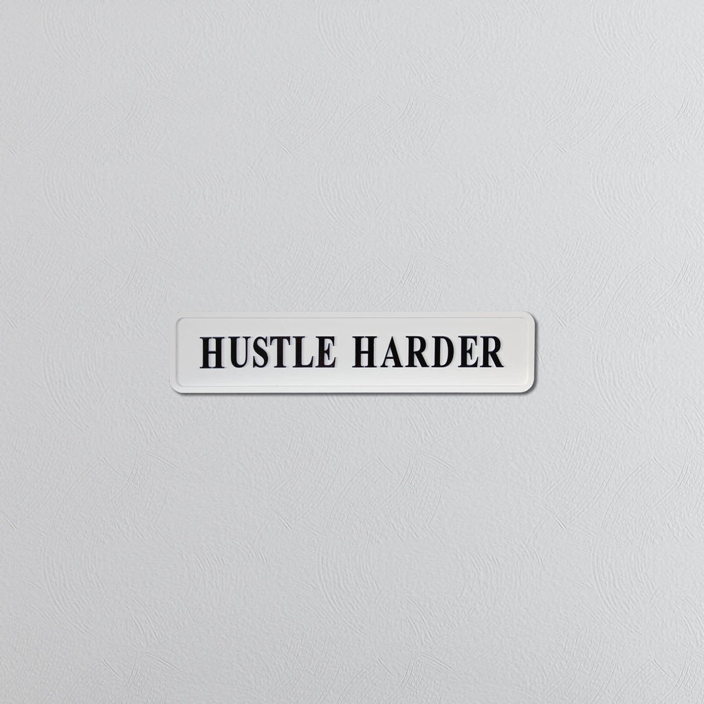 Motivational sign with 'HUSTLE HARDER' text on a light gray background