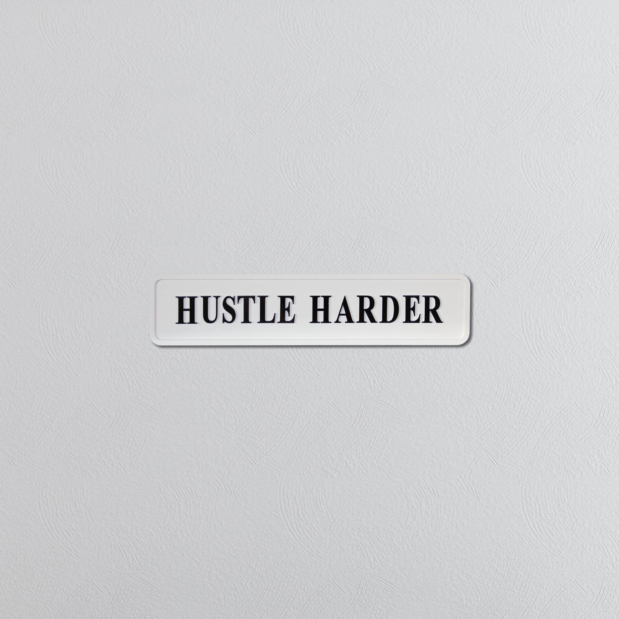 Motivational sign with 'HUSTLE HARDER' text on a light gray background