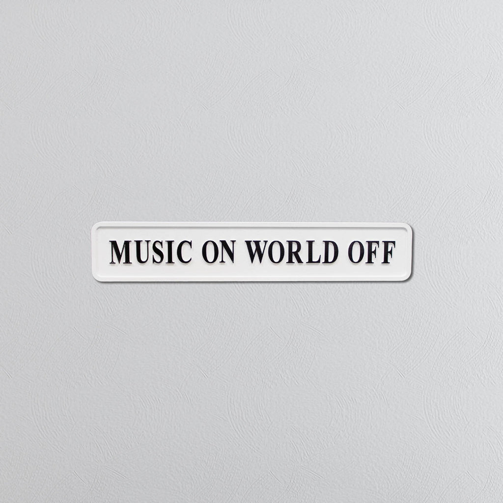 Rectangular sign with black text saying 'MUSIC ON WORLD OFF' on a gray background