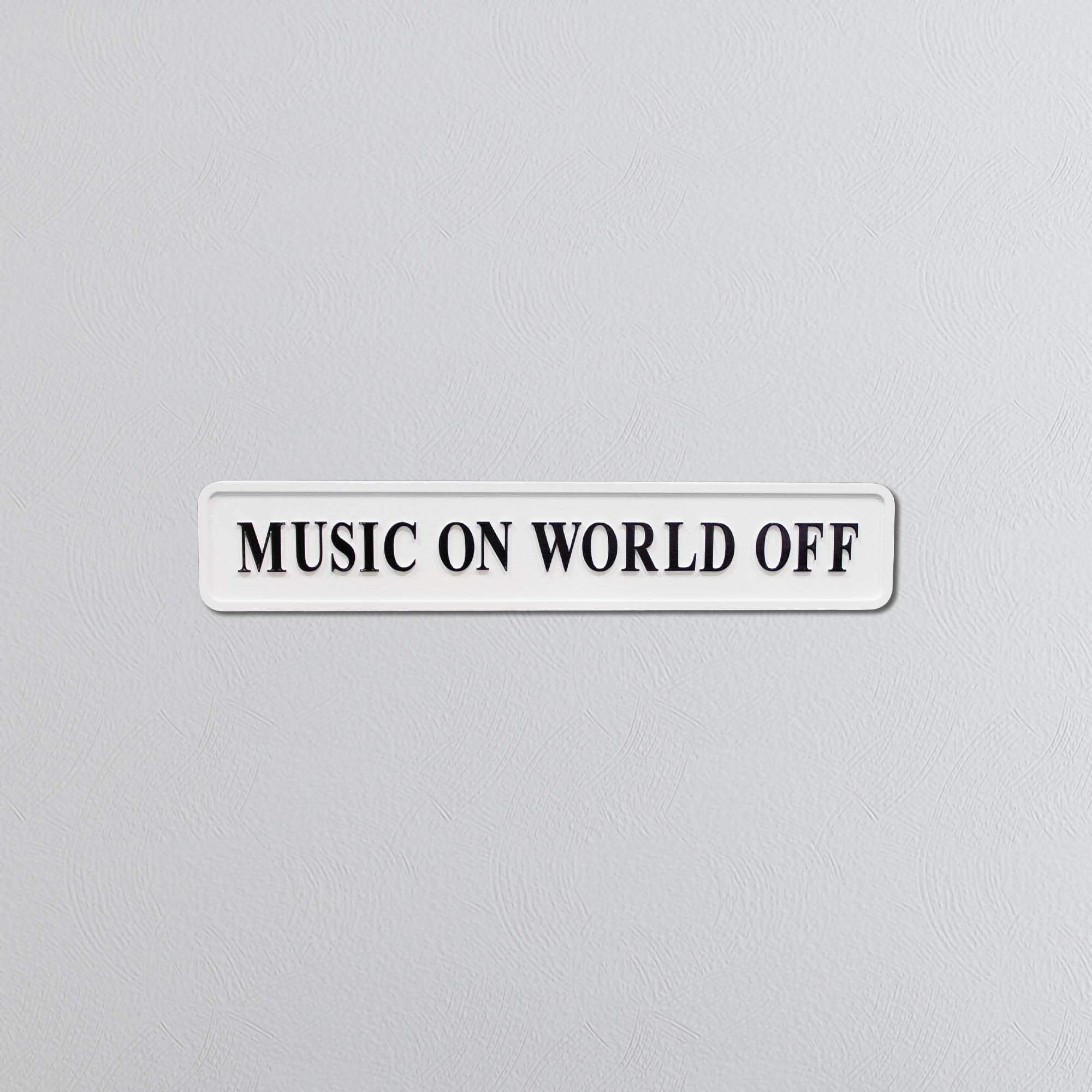 Rectangular sign with black text saying 'MUSIC ON WORLD OFF' on a gray background