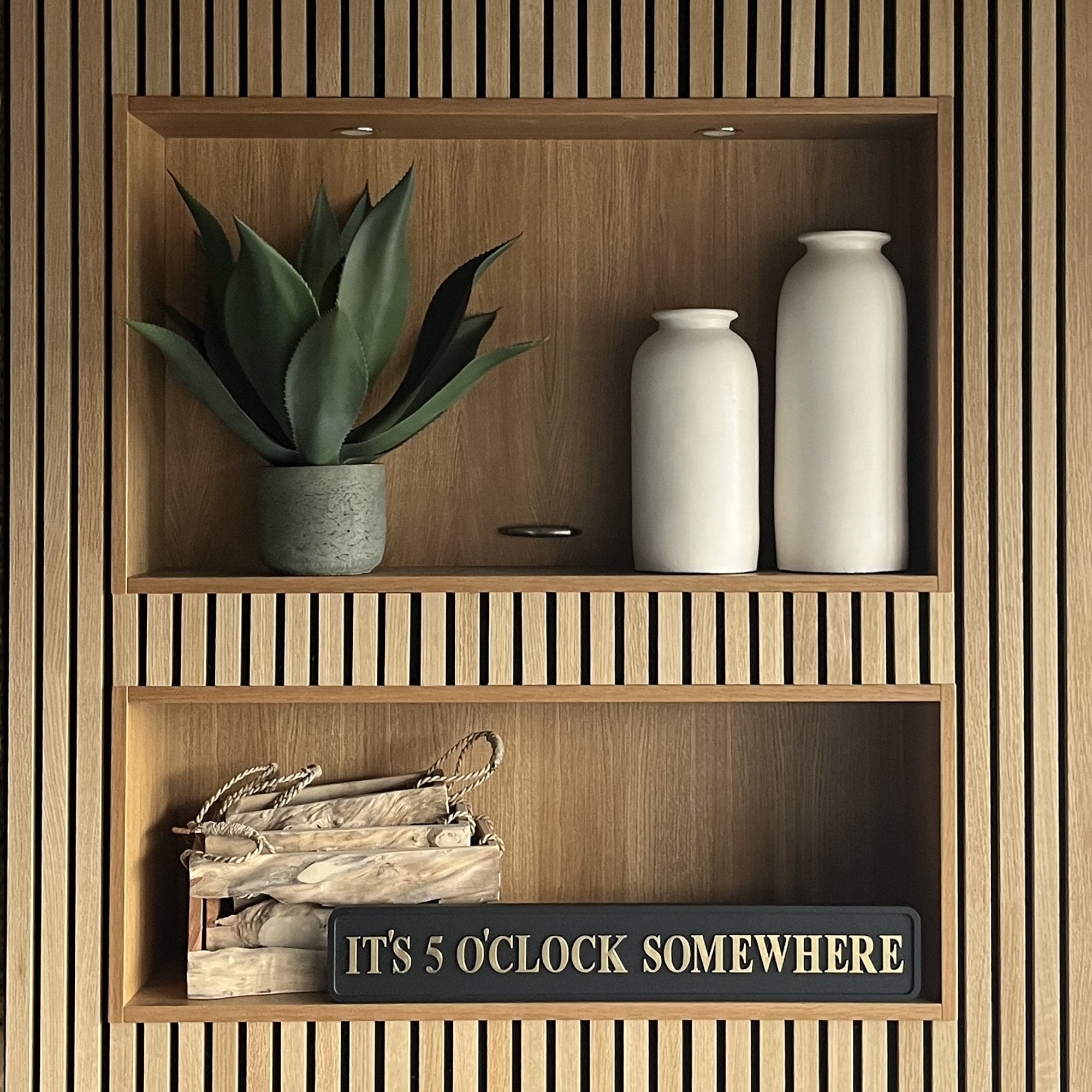 Wooden shelves with decorative items including a plant, vases, and a sign on a wooden wall.