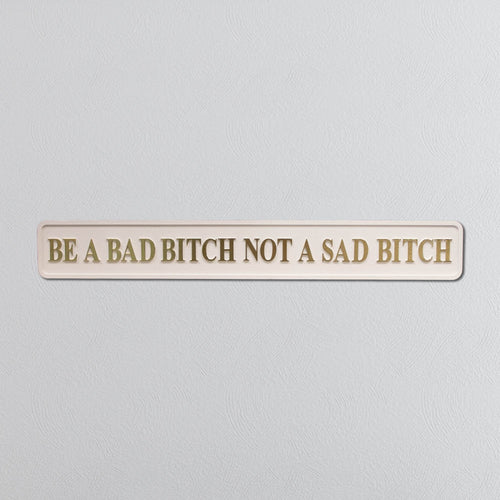Wooden sign with motivational quote 'Be a bad bitch not a sad bitch' on a light gray background