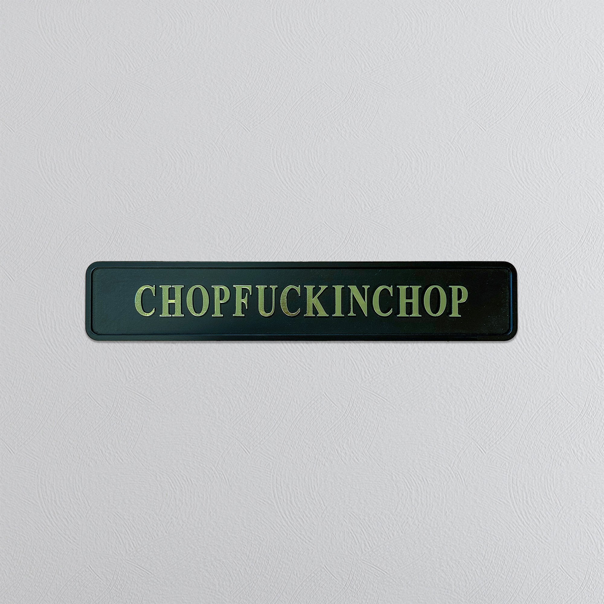 Rectangular sign with gold foil text 'CHOPFUCKINCHOP' on a light gray background