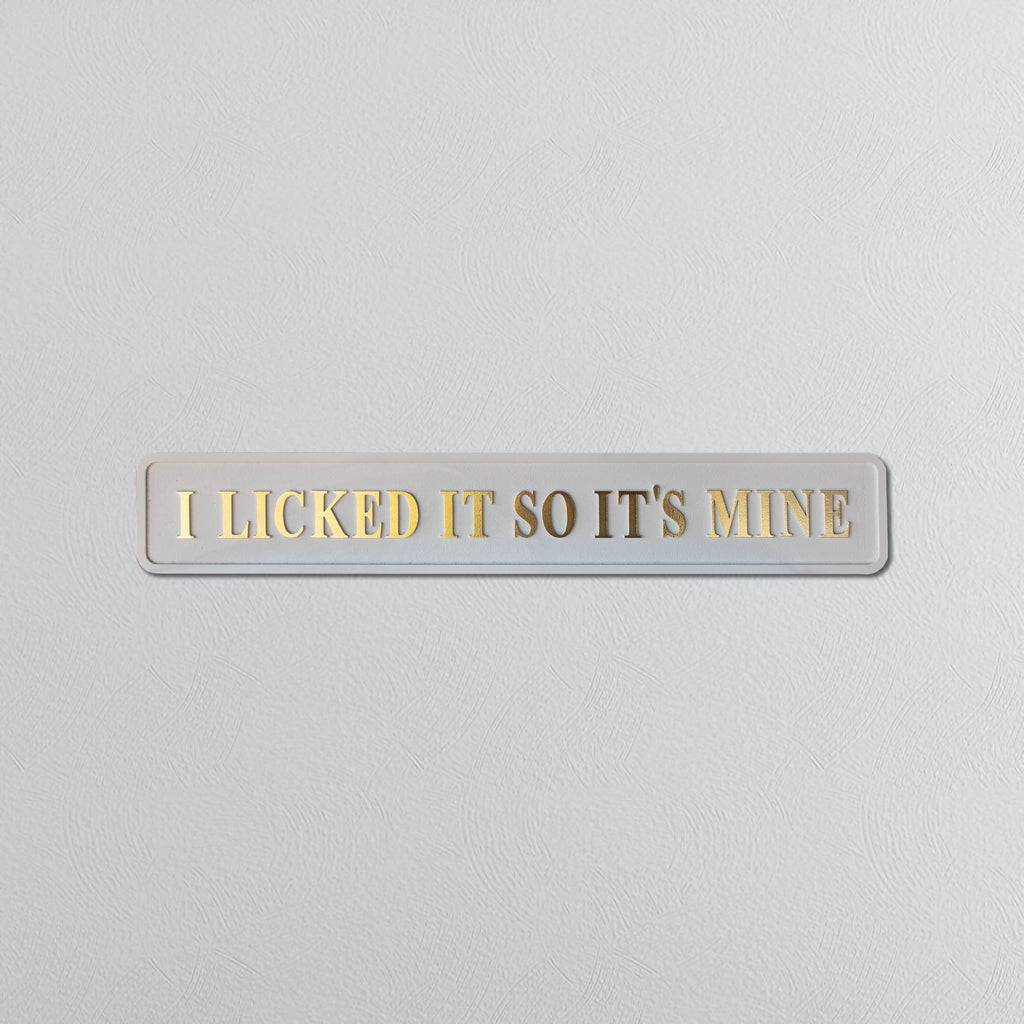 Wooden plaque with 'I Licked It So It's Mine' gold text on a light gray background