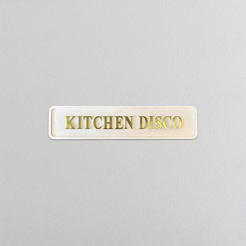 Rectangular sign with 'KITCHEN DISCO' text on a light gray background