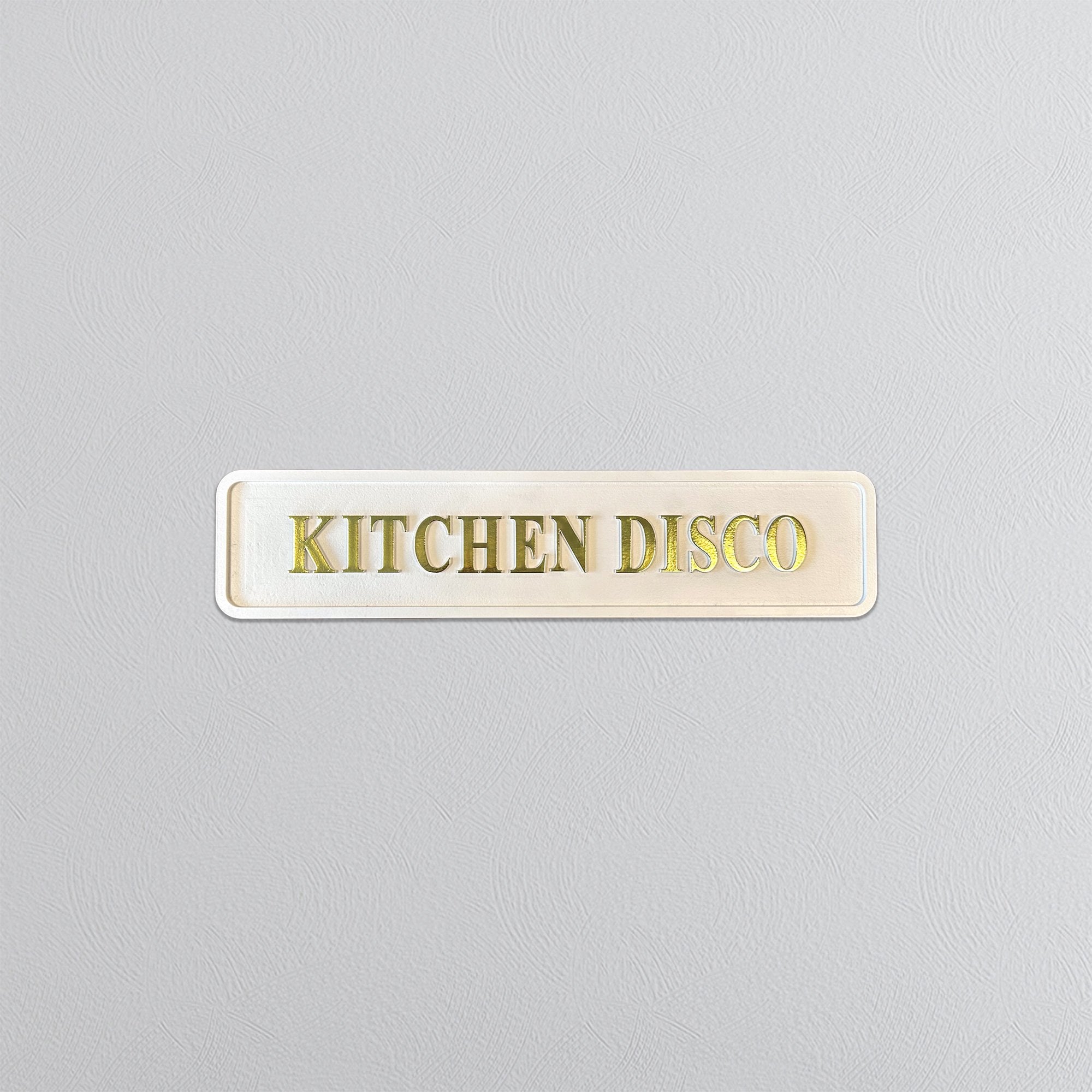 Rectangular sign with 'KITCHEN DISCO' text on a light gray background