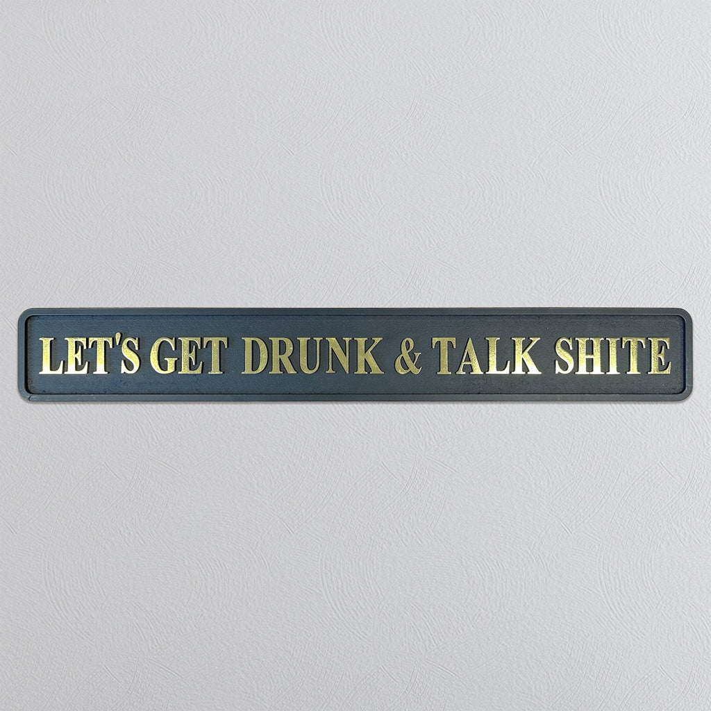 Decorative sign with gold text reading 'LETS GET DRUNK & TALK SHITE' on a gray background