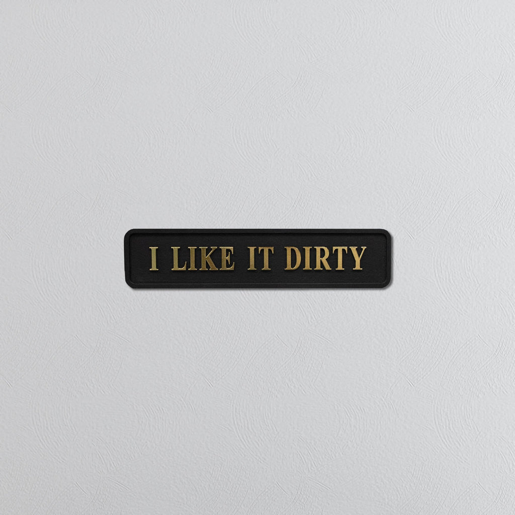 Black sign with gold text 'I LIKE IT DIRTY' on a light gray background