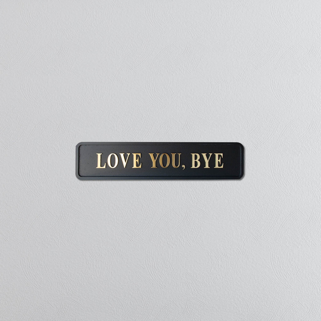 Black and gold foiled street sign with "love you, bye" lettering 