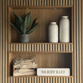 Wooden shelves with decorative items including a plant, vases, and a sign reading NO RIFF RAFF on a wooden wall.
