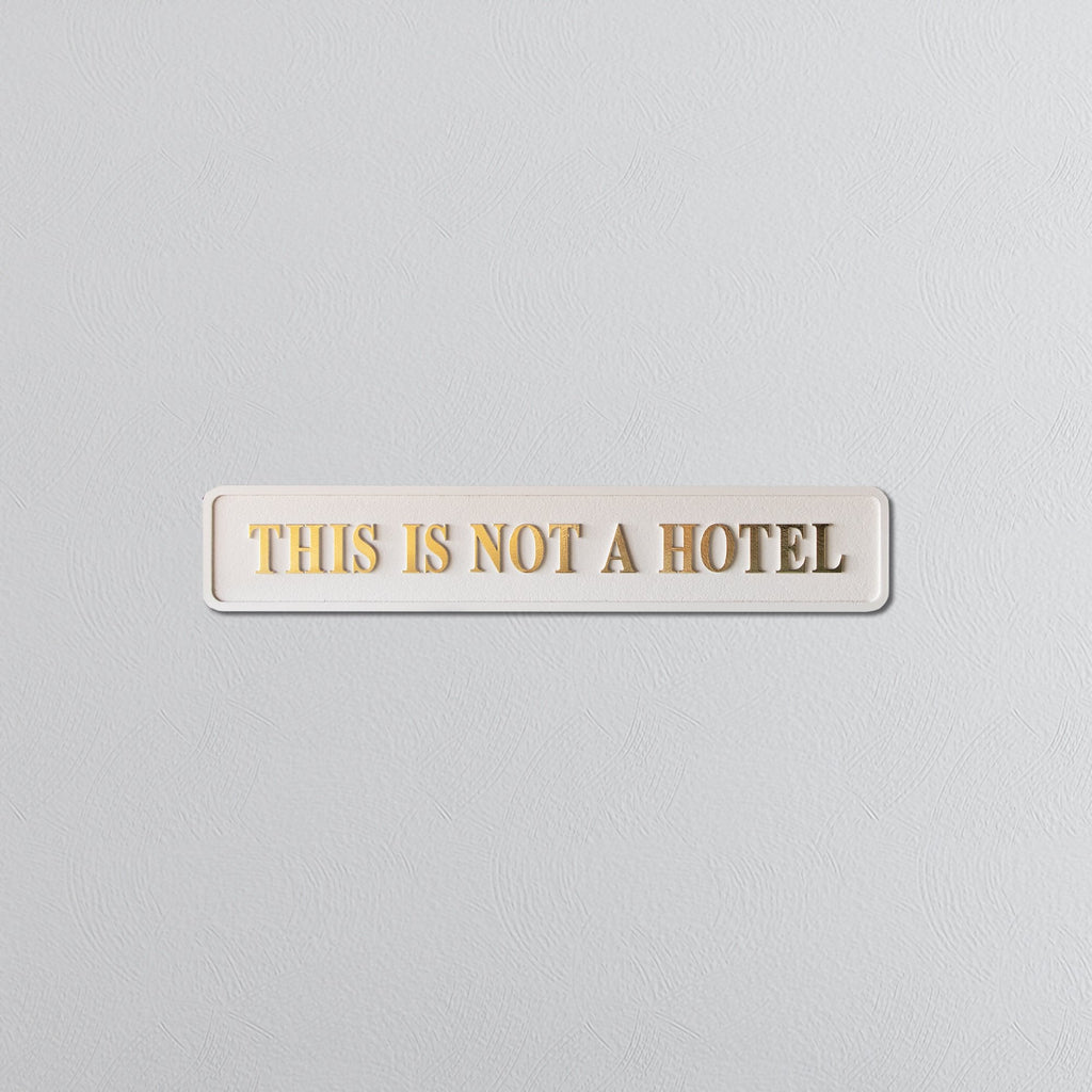 Cream sign on a white background with 'THIS IS NOT A HOTEL' gold text.