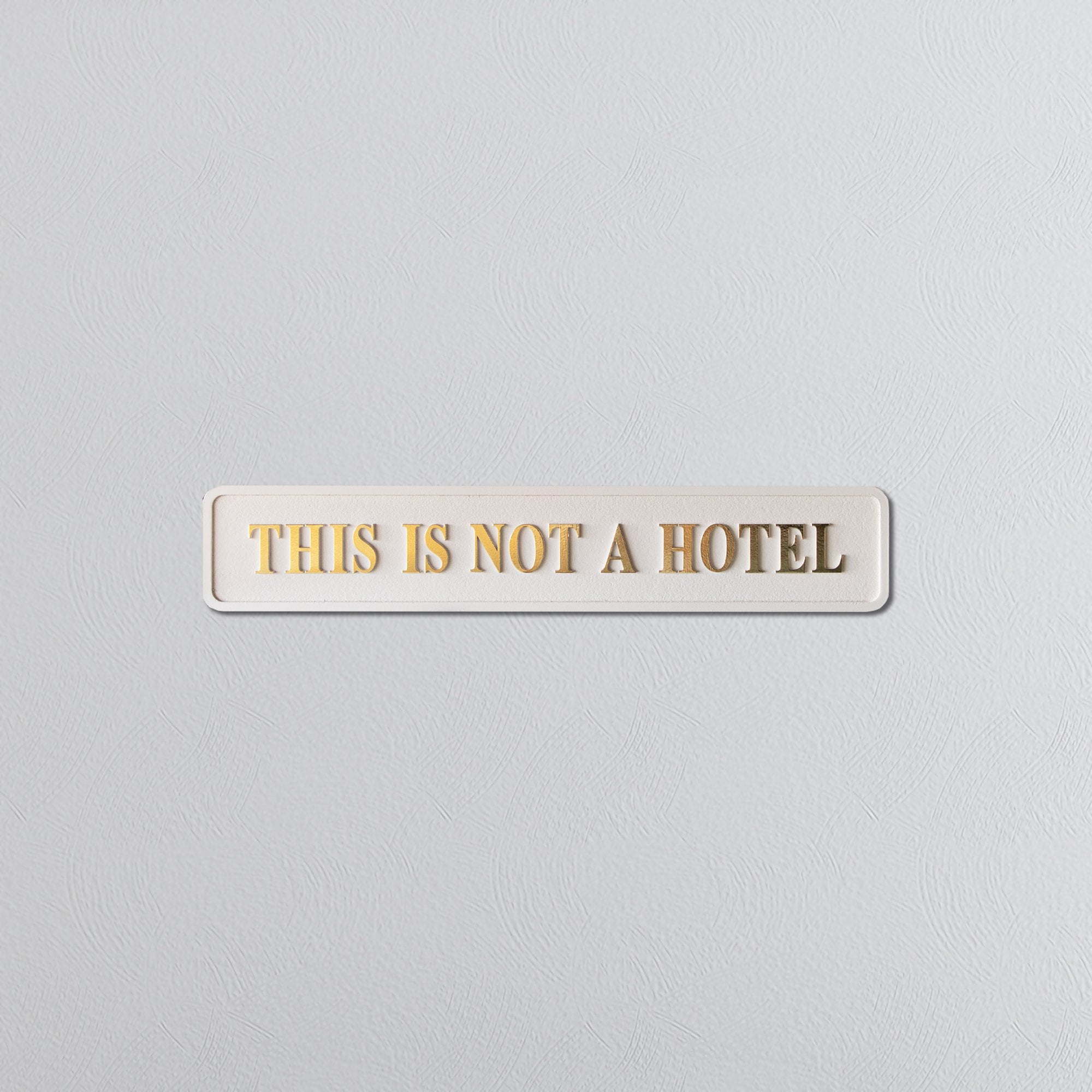 Cream sign on a white background with 'THIS IS NOT A HOTEL' gold text.