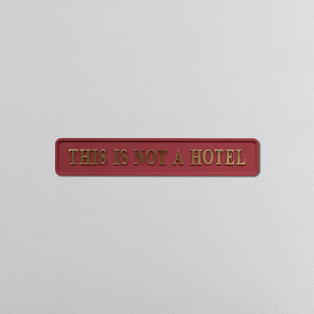Red sign with gold text 'THIS IS NOT A HOTEL' on a light gray background