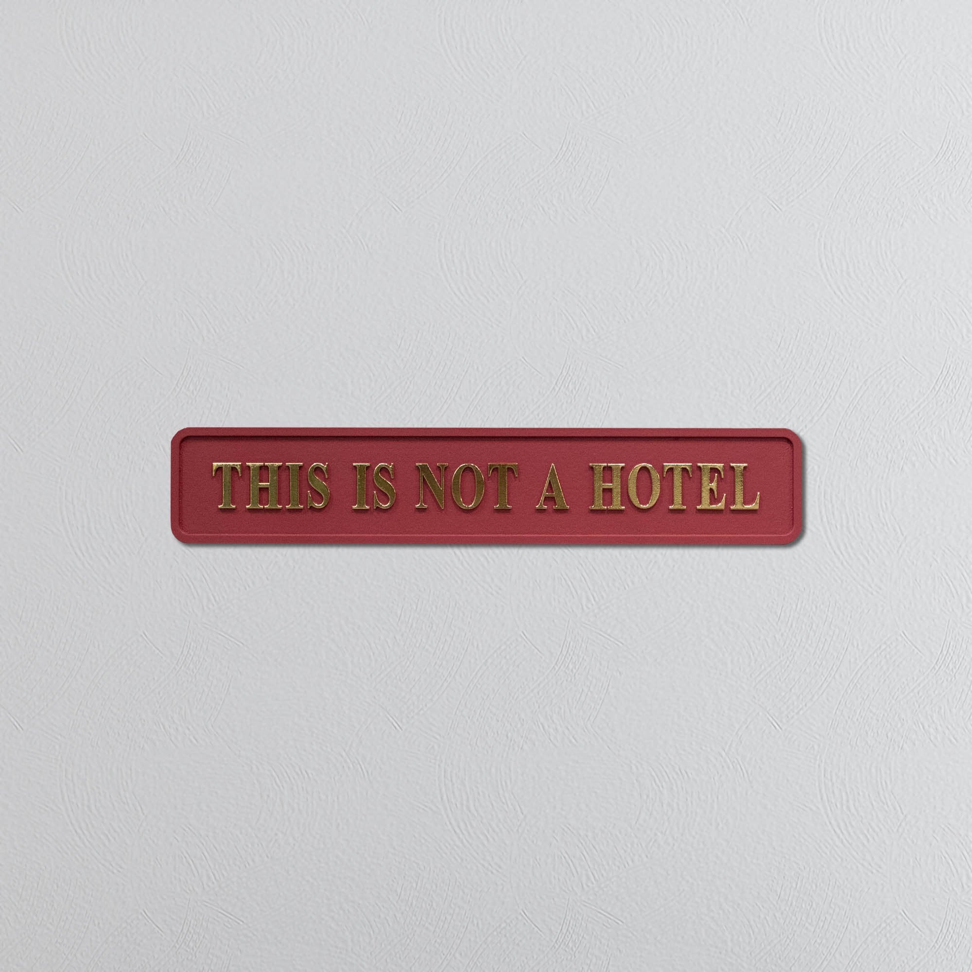 Red sign with gold text 'THIS IS NOT A HOTEL' on a light gray background