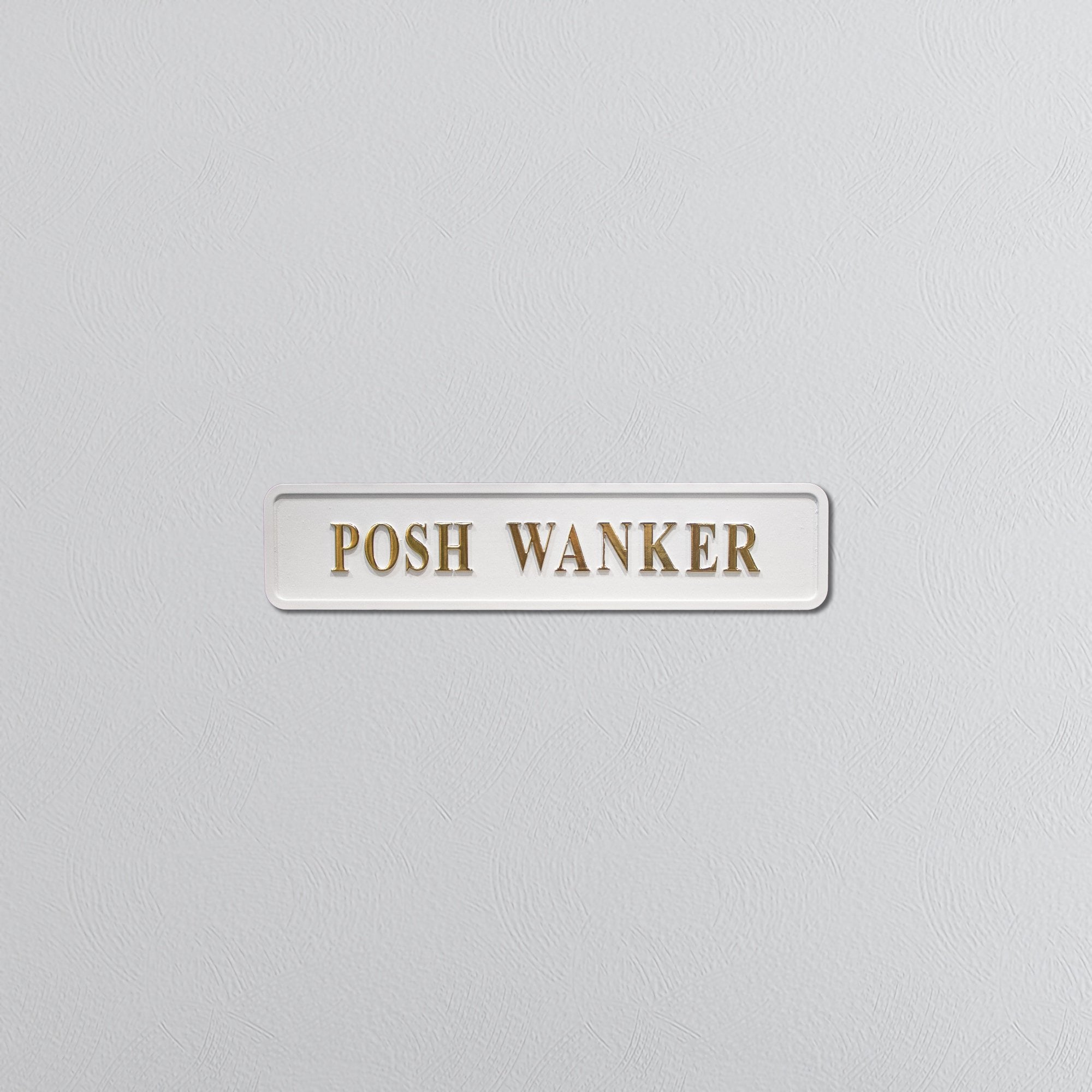 White rectangular sign with gold text saying 'POSH WANKER' on a light gray background