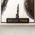 Decorative sign with 'SOTALLY TOBER' text in front of abstract art
