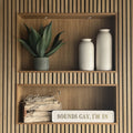 Wooden shelves with decorative items including a plant, vases, and a sign reading 'SOUNDS GAY I'M IN' with gold letters on a striped wall.
