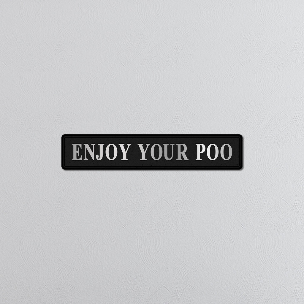 Black sign with silver text 'ENJOY YOUR POO' on a light gray background