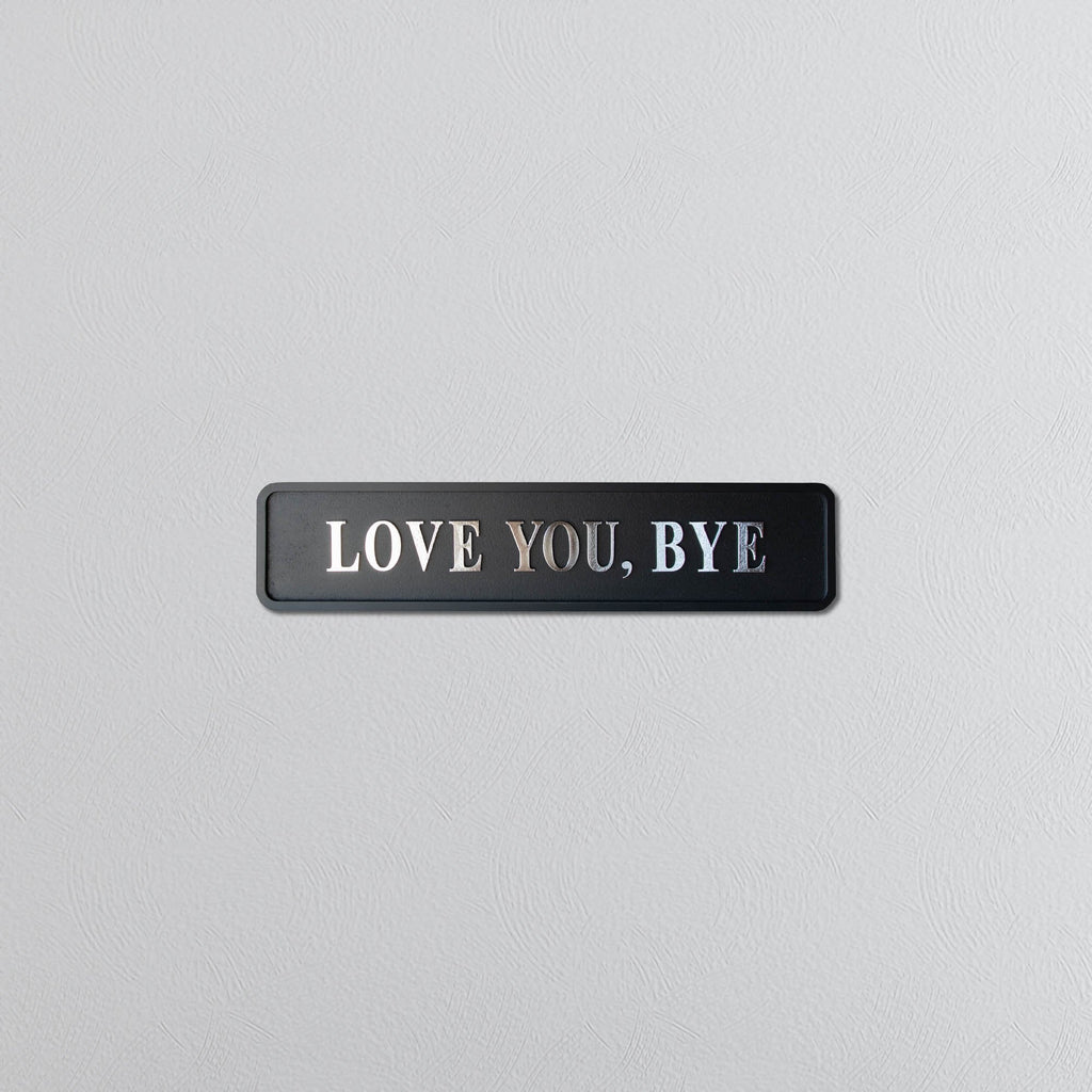 Black and silver foiled street sign with "love you, bye" lettering