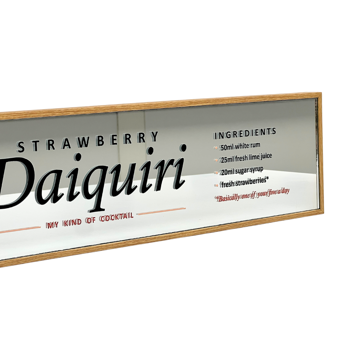 A rectangular framed wall sign featuring a white background with the words 'STRAWBERRY Daiquiri' in large black lettering, plus a small ingredients list and red text reading 'MY KIND OF COCKTAIL.' The sign has a light natural wood frame and is photographed against a plain white background.