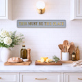 Kitchen counter with decorative items and a grey sign reading 'THIS MUST BE THE PLACE' with gold text.