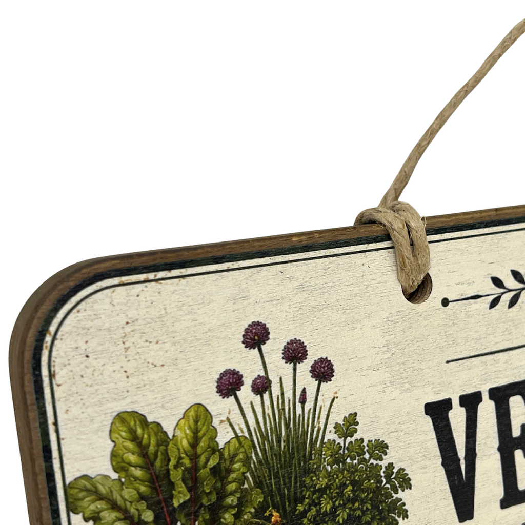 A close-up of a rustic decorative hanging sign with a cream distressed background, botanical illustrations including green leaves and purple flowers, and partial black lettering, suspended by a twine loop.