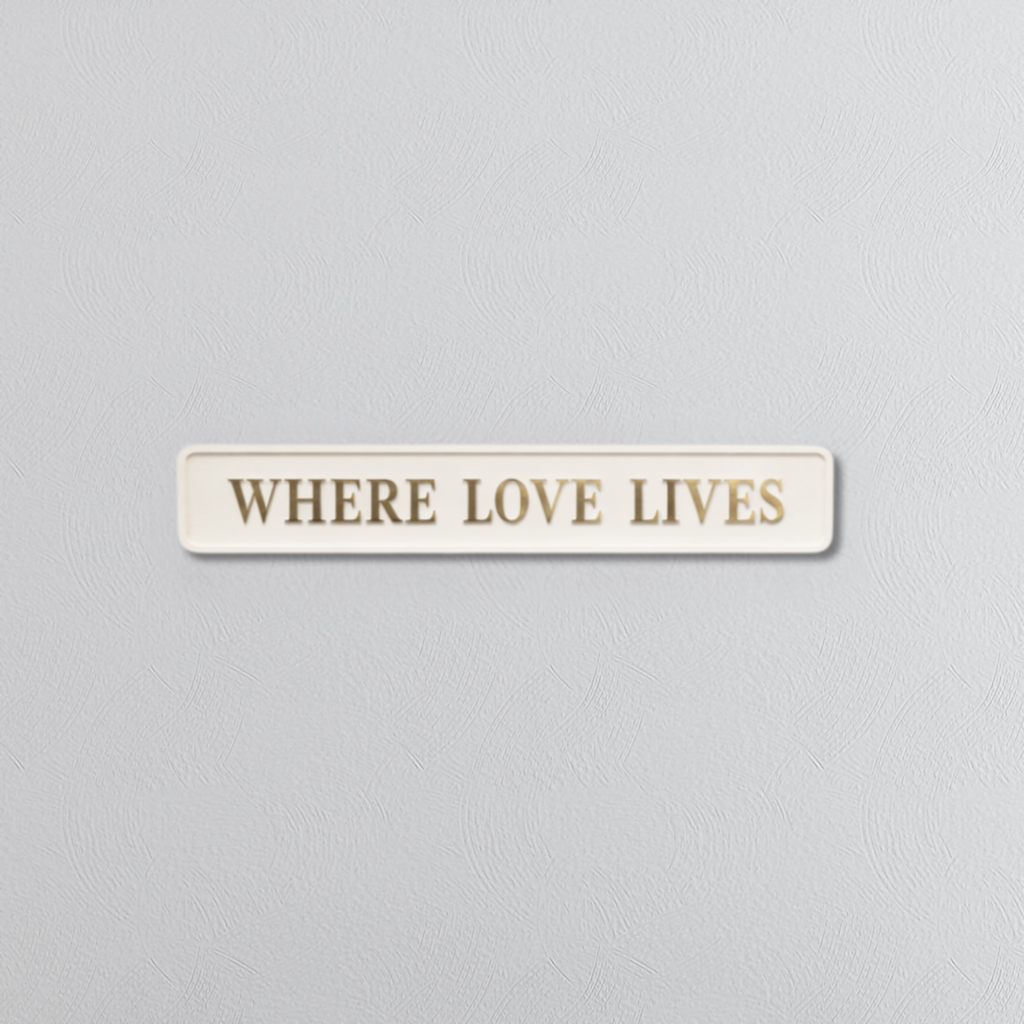 Decorative sign with WHERE LOVE LIVES in gold foil text on a grey background