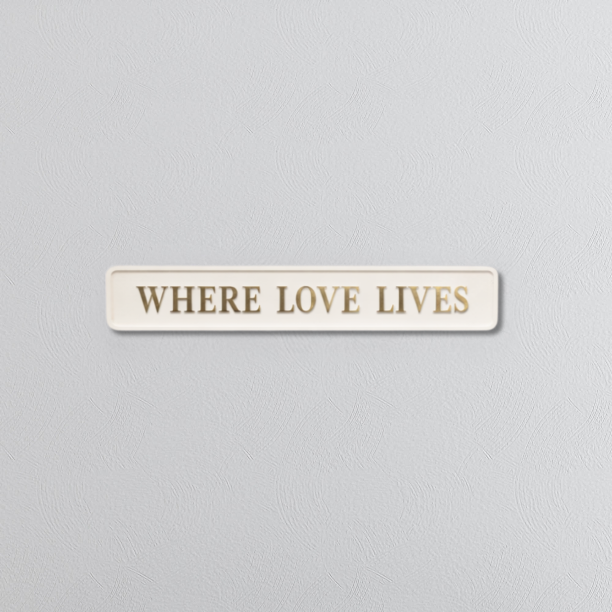 Decorative sign with WHERE LOVE LIVES in gold foil text on a grey background