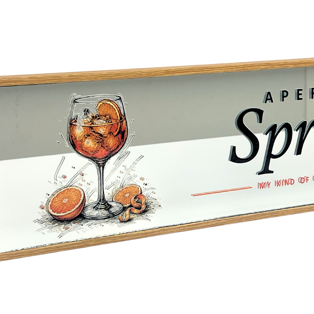 A rectangular decorative sign with a light wood frame, featuring an illustration of a wine glass filled with an orange cocktail and orange slices on a white background, alongside partial black text reading 'APER Spr.