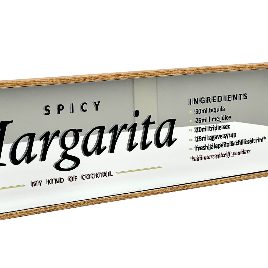 A rectangular glass cocktail sign with a light wood frame, featuring the text 'SPICY Margarita' and a list of ingredients on a white background.